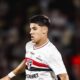 Jogador jovem com camisa branca do São Paulo, logotipo SPFC visível, em campo