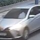 Carro sedan prateado com farol aceso em baixa qualidade de câmera de segurança