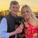 Casal sorrindo, homem e mulher, segurando um cachorro dachshund preto e marrom