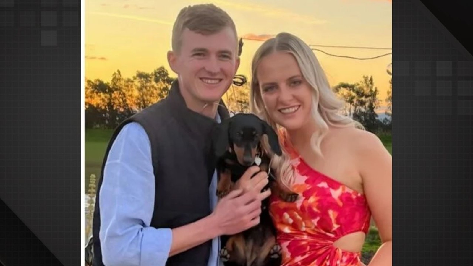 Casal sorrindo, homem e mulher, segurando um cachorro dachshund preto e marrom
