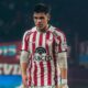 Homem jovem em camisa de futebol listrada vermelha e branca em campo