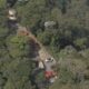Vista aérea de estrada em floresta densa com viaturas de emergência e uma estrutura de pagode