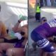 Homem de camisa roxa agride atletas sentadas em quadra de vôlei de praia