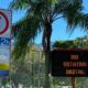 Placa de estacionamento Rio Rotativo Digital e painel luminoso em área verde com palmeira.