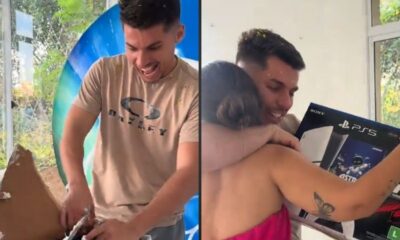 Homem sorridente com confete, abraçando mulher e segurando caixa de PlayStation 5