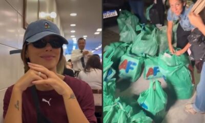 Bruna Biancardi com boné e óculos escuros sorri; ao lado, diversas sacolas verdes de compras no chão