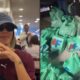Bruna Biancardi com boné e óculos escuros sorri; ao lado, diversas sacolas verdes de compras no chão