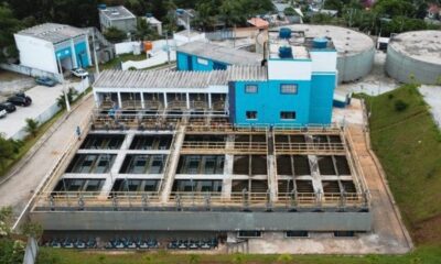 Vista aérea de estação de tratamento de água com tanques, edifícios azuis, e tanques circulares