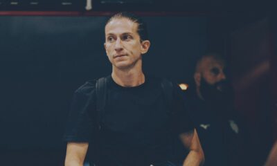 Filipe Luís, de camiseta preta e mochila, olhando para o lado esquerdo em ambiente escuro.