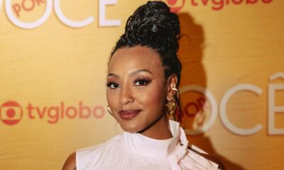 Sheron Menezzes sorri, cabelo trançado, brincos de ouro em evento "Por Você" TV Globo