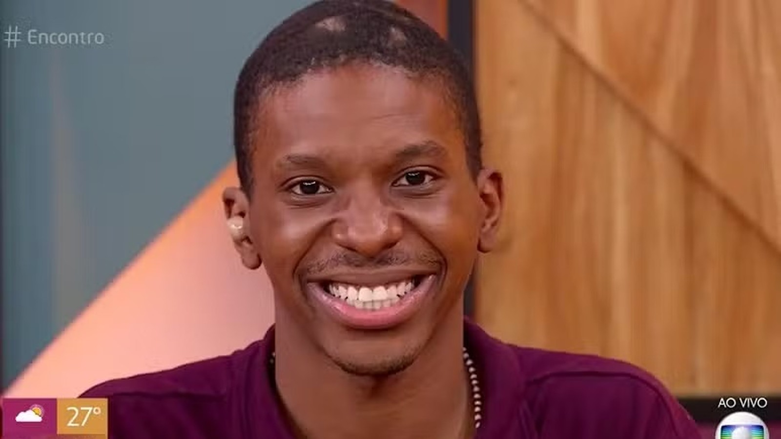 Jovem negro sorrindo em tela de TV, com # Encontro e AO VIVO na tela