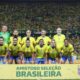Seleção brasileira feminina posa em campo, estádio lotado. Faixa com "AMISTOSO SELEÇÃO BRASILEIRA", CBF e USA
