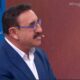 Ratinho de perfil, com bigode, óculos azuis, terno. Microfone no rosto. Textos #ProgramaDoRatinho, AO VIVO