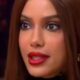 Close-up de mulher com cabelo castanho, batom vermelho, maquiagem escura nos olhos e boca levemente aberta