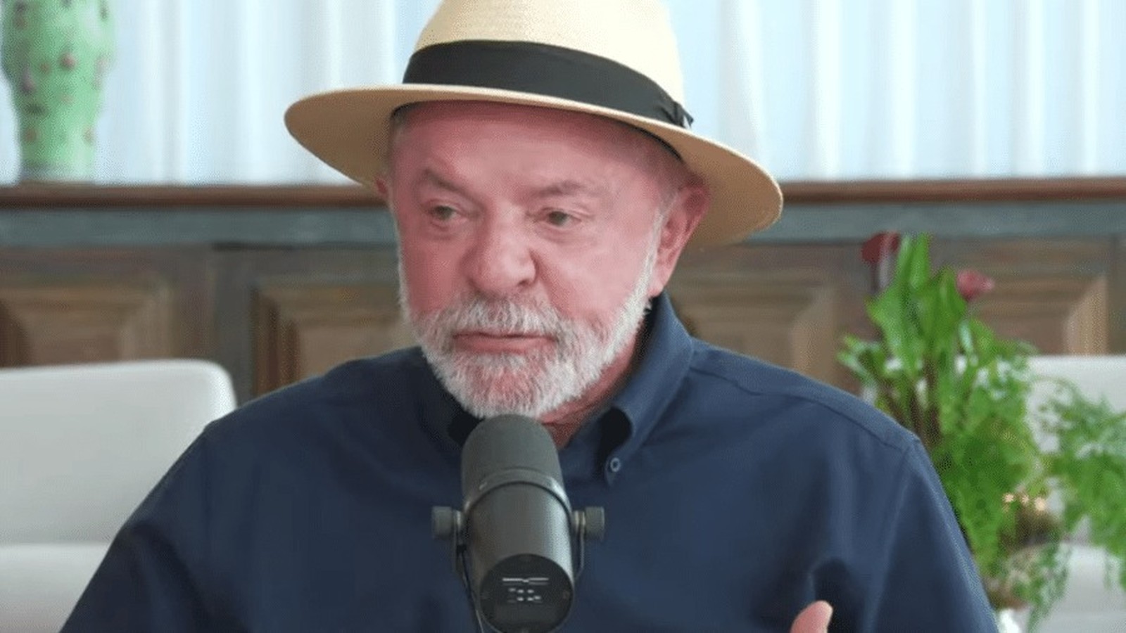 O presidente Lula da Silva, usando um chapéu de palha, barba grisalha, camisa azul, fala ao microfone