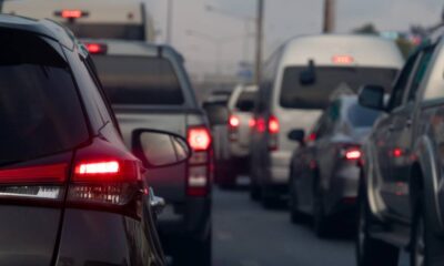 Vista traseira de vários carros em engarrafamento com as luzes de freio acesas na rua.