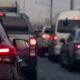 Vista traseira de vários carros em engarrafamento com as luzes de freio acesas na rua.