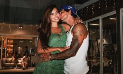 Gabriel Medina beija Isabella Arantes na bochecha, sorridentes e abraçados, em ambiente interno