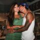 Gabriel Medina beija Isabella Arantes na bochecha, sorridentes e abraçados, em ambiente interno