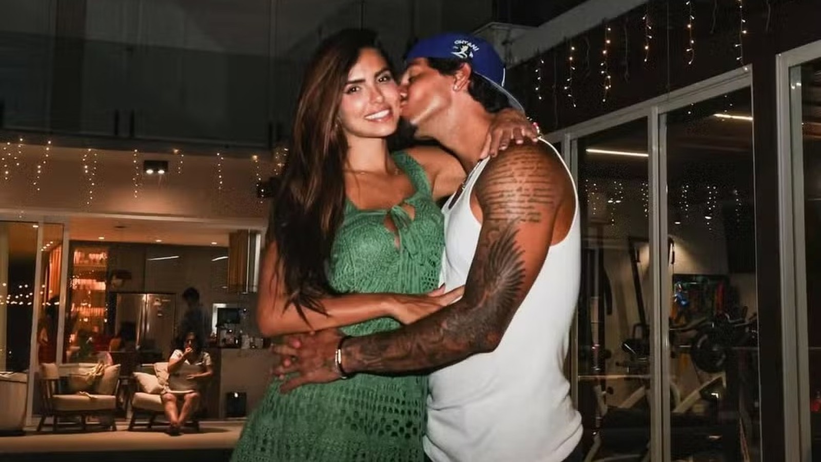 Gabriel Medina beija Isabella Arantes na bochecha, sorridentes e abraçados, em ambiente interno