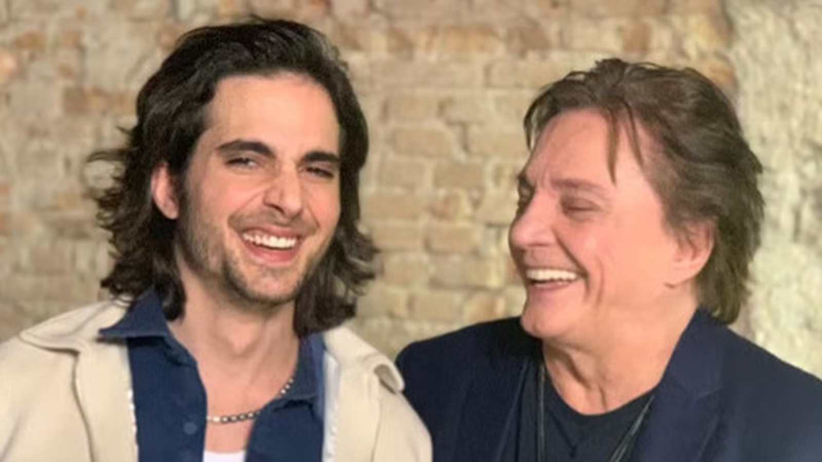 Fiuk e Fábio Jr. sorrindo e rindo, o mais jovem com cabelo comprido e o mais velho ao lado