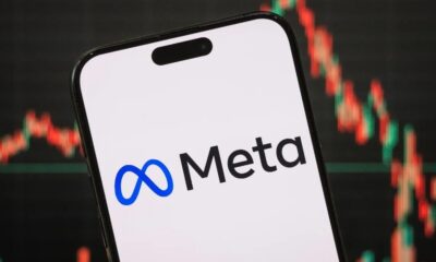 Smartphone com logotipo e nome Meta em tela, e gráfico financeiro desfocado ao fundo