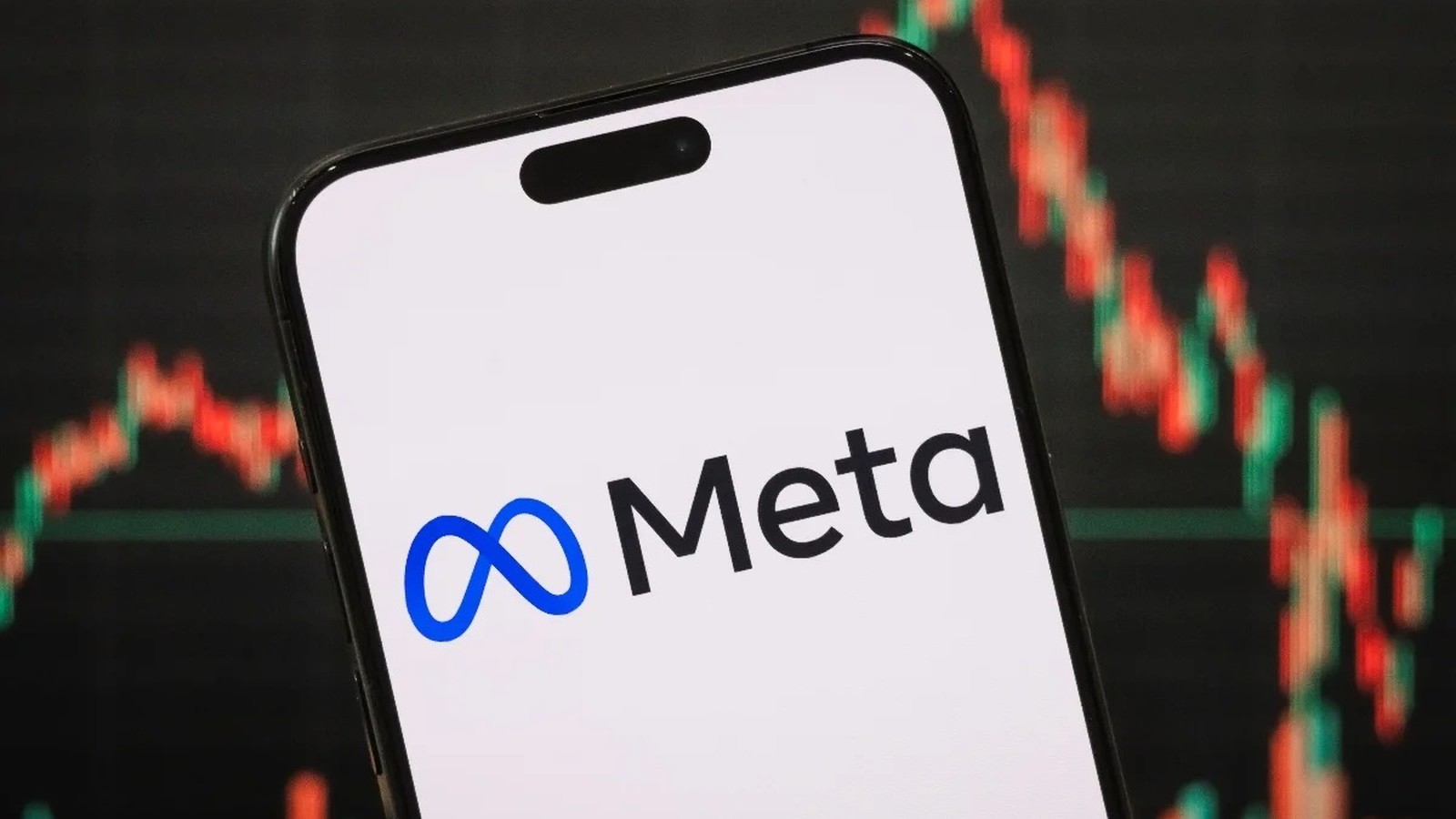 Smartphone com logotipo e nome Meta em tela, e gráfico financeiro desfocado ao fundo