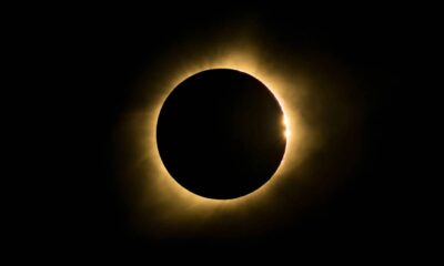 Eclipse solar total com disco escuro, halo luminoso e um ponto de luz brilhante