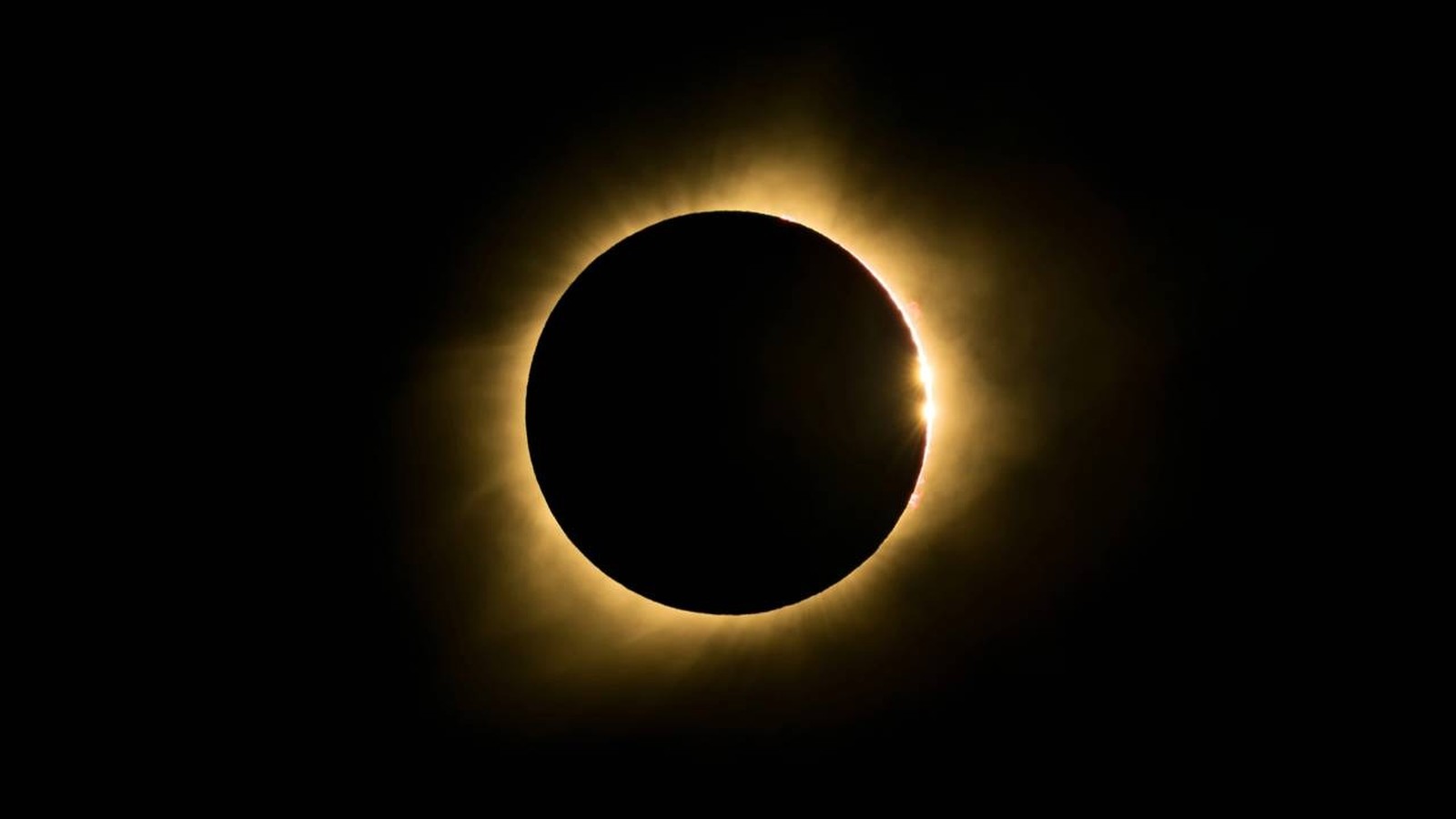 Eclipse solar total com disco escuro, halo luminoso e um ponto de luz brilhante