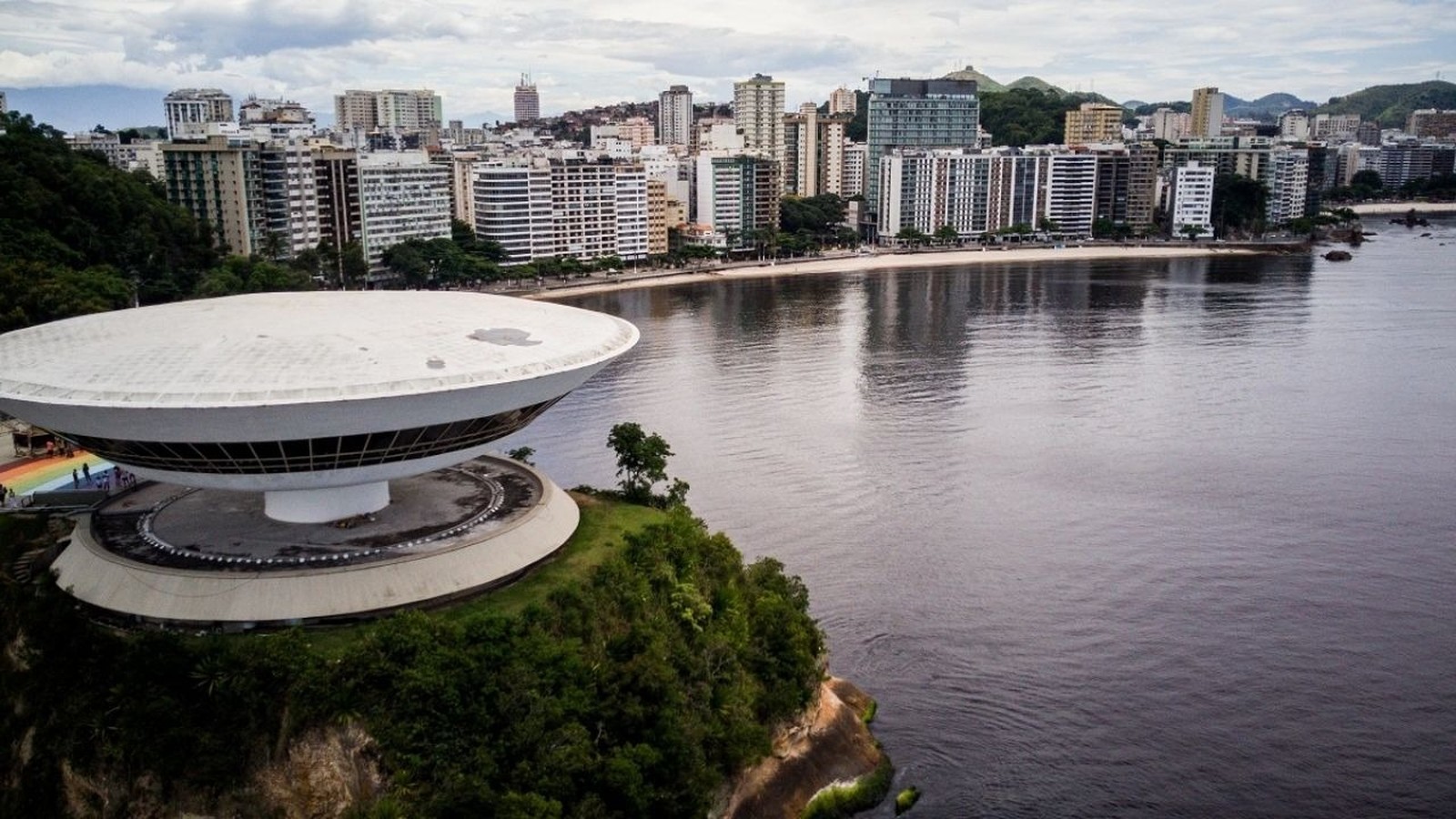 Museu de Arte Contemporânea de Niterói e cidade costeira sob céu nublado