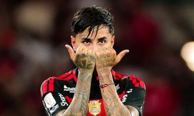 Jogador Erick Pulgar com camisa rubro-negra ergue as mãos tatuadas com polegares para cima