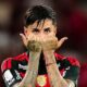 Jogador Erick Pulgar com camisa rubro-negra ergue as mãos tatuadas com polegares para cima