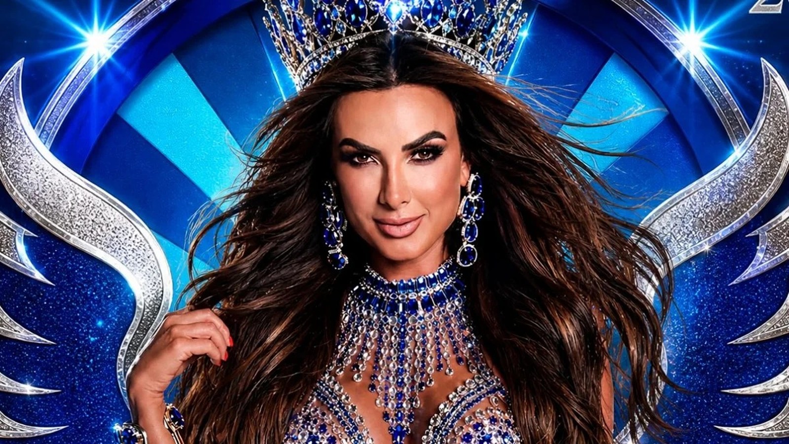 Nicole Bahls sorrindo, com coroa azul, joias exuberantes, em fundo carnavalesco azul e prata