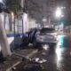 SUV prateado chocado contra muro de prédio à noite, com porta aberta e destroços