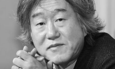 Retrato em preto e branco do diretor Ahn Pan Seok, cabelo médio, mãos unidas