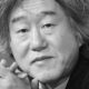 Retrato em preto e branco do diretor Ahn Pan Seok, cabelo médio, mãos unidas