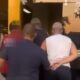 Agentes conduzem homens à entrada de prédio da Polícia Civil ao entardecer