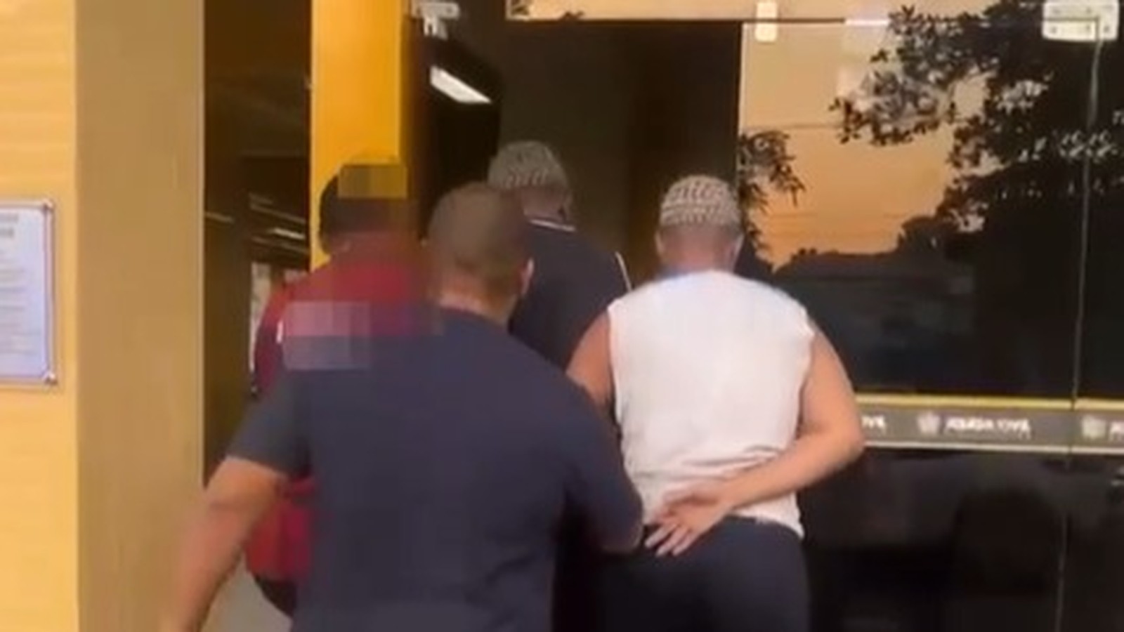 Agentes conduzem homens à entrada de prédio da Polícia Civil ao entardecer