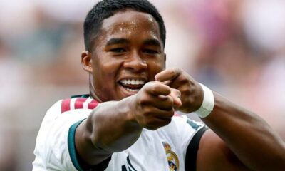 Jogador Endrick, com a camisa do Real Madrid, sorri e aponta para frente