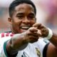 Jogador Endrick, com a camisa do Real Madrid, sorri e aponta para frente