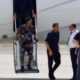 Ronaldinho Gaúcho descendo escada de avião com seguranças e policial no tarmac