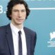 Adam Driver de terno azul, camisa branca, gravata, sorrindo em fundo azul com ‘28. 7.09’