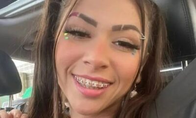 Jovem mulher sorrindo com cabelos longos, aparelho ortodôntico, maquiagem vibrante e piercing na sobrancelha