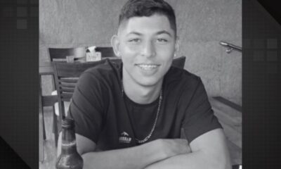Foto em preto e branco de um jovem sorrindo com aparelho nos dentes