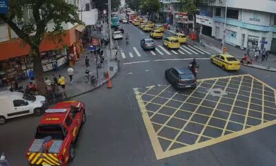 Vista aérea de rua movimentada com caminhão de bombeiros, táxis e pessoas no cruzamento