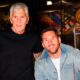 Lionel Messi sorri ao lado de homem de cabelo grisalho em quadra de futebol coberta