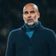 Pep Guardiola, careca e barbudo, em suéter azul escuro, com olhar pensativo