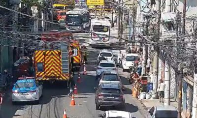 Caminhão de bombeiros e carro de polícia em rua urbana com tráfego congestionado e cones