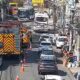 Caminhão de bombeiros e carro de polícia em rua urbana com tráfego congestionado e cones