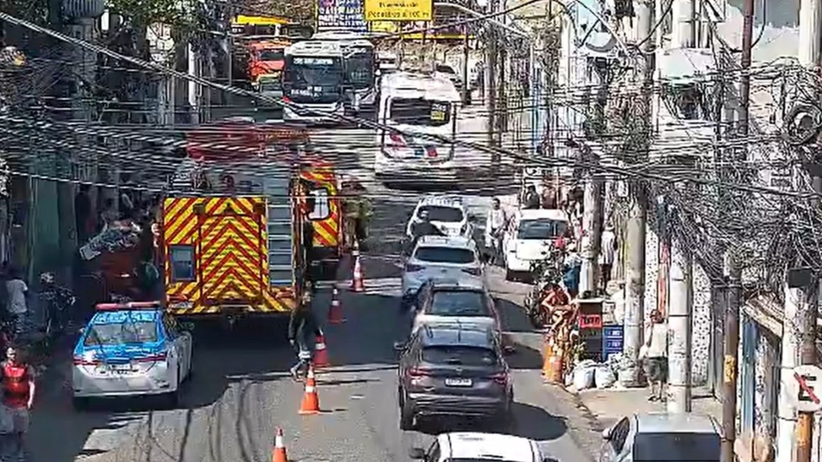 Caminhão de bombeiros e carro de polícia em rua urbana com tráfego congestionado e cones